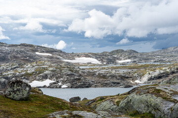 Rocky landscape with scattered lakes and moody clouds in Norway.