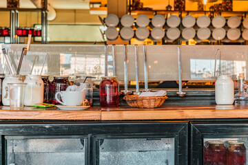 Glass jars with sour cream and compote with mane ladles on the classic kitchen at restaurant. Decor. Decoration. Farm