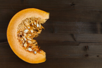 Fresh organic pumpkin slice on dark wooden background.