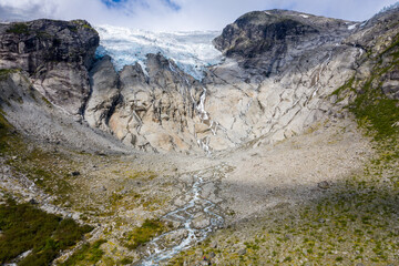Dramatic rock formations surrounding a glacier in Norway, highlighting the rugged beauty of the landscape.