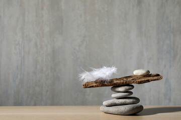 Stack of stones with tree branch and feather against grey background, space for text. Balance...