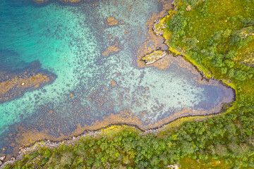 Aerial view of vibrant turquoise coastal waters in the Lofoten Islands, Norway.
