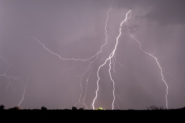 Multiple lightning strikes near and on a farm silo in the distance during a 2014 Arizona Monsoon storm.