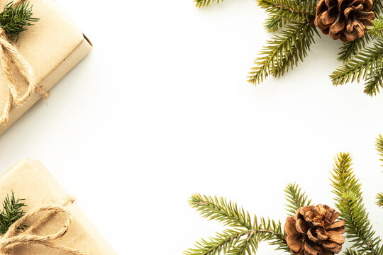 Beautiful Christmas background with two gift boxes, decorate with pine branch and pine cone over white background. Top view with copy space, flay lay.