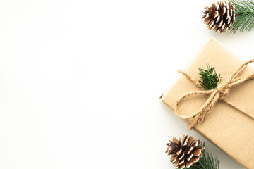 Beautiful Christmas background with gift box, decorate with pine branch and pine cone over white background. Top view with copy space, flay lay.