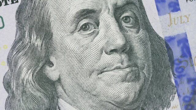 Close up shot of the rotating Benjamin Franklin's face on the 100 hundred dollar bill. Business concept of the financial capital and investment to the stock. Economy success with money and cash.