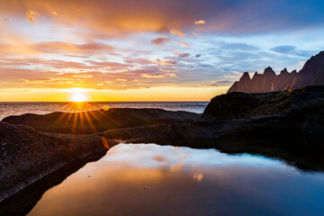 Midnight sun over the fjord and mountain peaks known as Devil's Teeth, Tungeneset viewpoint, Senja, Troms county, Norway, Scandinavia