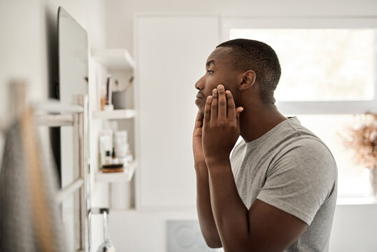 Young man African examining his complexion in his bathroom