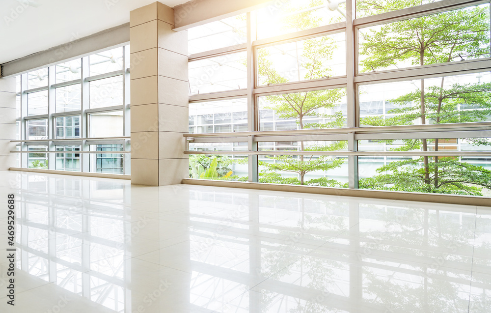 Poster empty corridor in modern office building with green tree outside the window