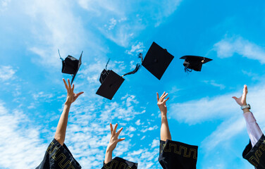 Four graduates throwing graduation hats in the air