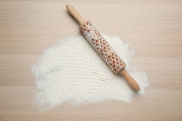 Rolling pin and flour on wooden background, top view. Space for text
