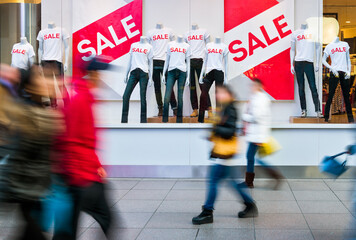 People walking through the window display with text SALE