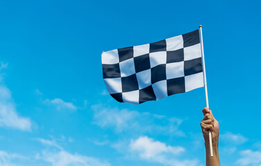 Hand holding checkered race flag in the air