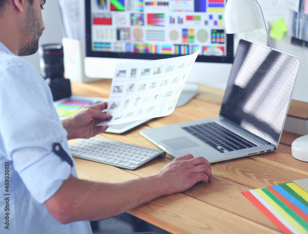 Poster portrait of young designer sitting at graphic studio in front of laptop and computer while working o