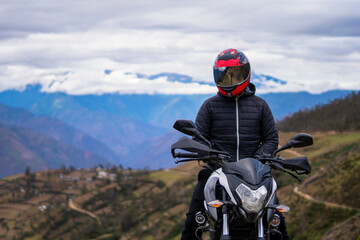 man riding a motorcycle on top of a mountain looking at the horizon
