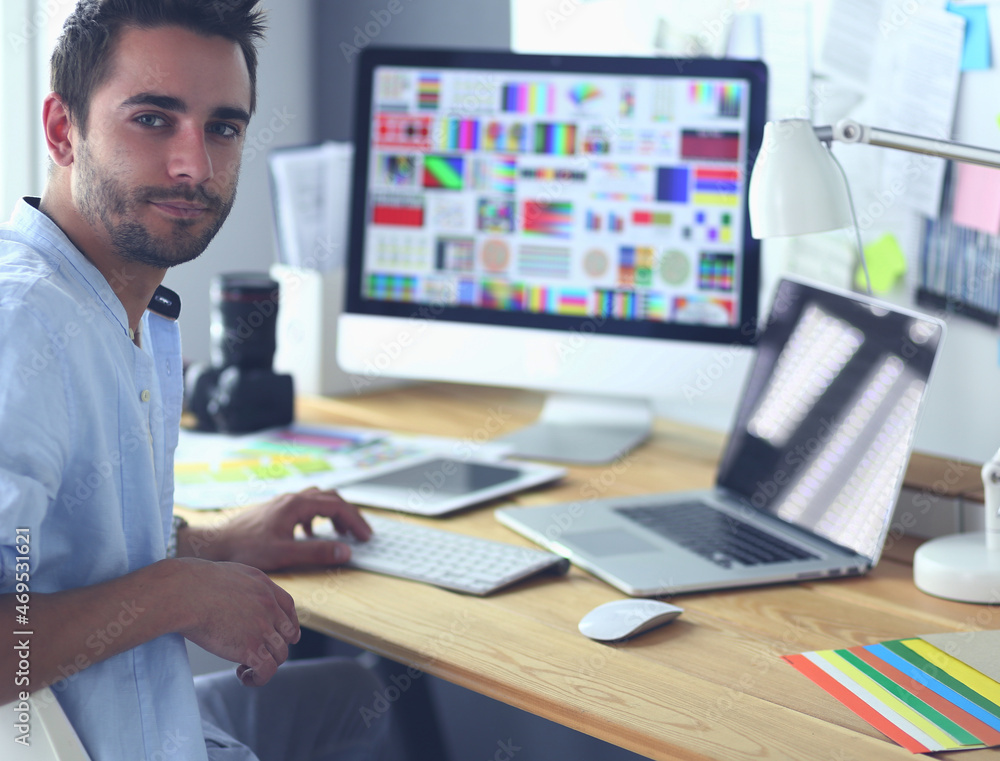 Poster portrait of young designer sitting at graphic studio in front of laptop and computer while working o