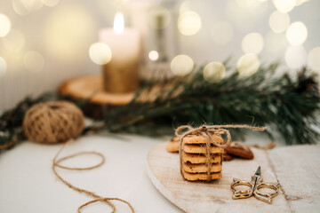 Cozy Christmas mood. Craft homemade cookies Christmas tree shape in wooden tray on table with fir tree branch and candles