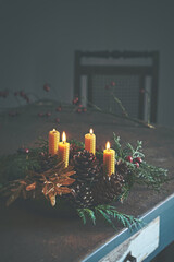 Christmas wreath with bee wax candles on an old kitchen table