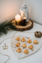 Cozy Christmas mood. Craft homemade cookies Christmas tree shape in wooden tray on table with fir tree branch and candles