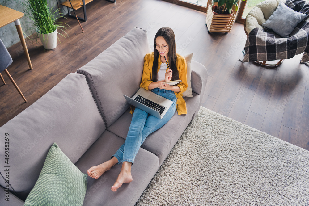 Sticker Top view photo of pretty shiny young lady dressed yellow shirt writing planner working modern gadget smiling indoors room home house