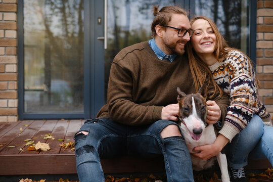Spouses and Bull Terrier resting on steps against front door