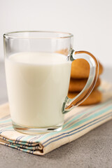 In the foreground is a cup of milk, in the background a blurry image of a cookie.