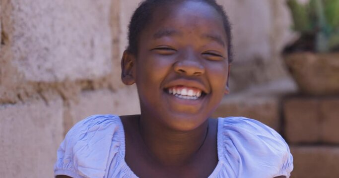 Poverty. Inequality. Portrait. Cute young Black African girl laughing and looking at camera