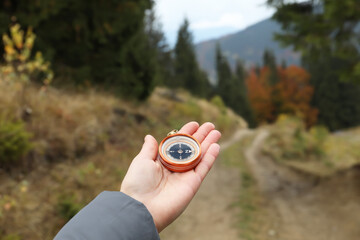 Woman using compass during journey in mountains, closeup