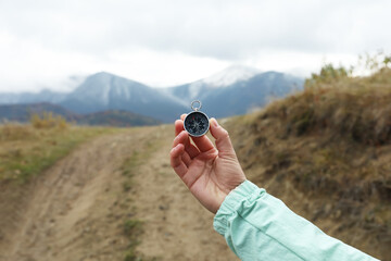 Fototapeta na wymiar Woman using compass during journey in mountains, closeup