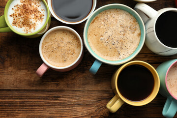 Many cups of different coffees on wooden table, flat lay