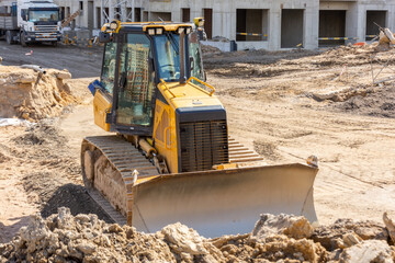 Powerful heavy crawler bulldozer works at a construction site. - obrazy, fototapety, plakaty