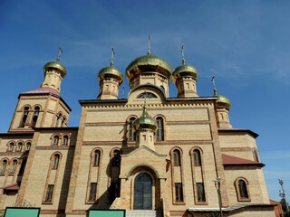Obraz premium A modern Christian church, made of yellow bricks, with gilded domes.