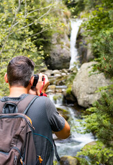 Photographer taking pictures of a waterfall in the mountain