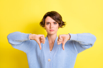 Photo of strict serious lady show thumbs down disliking wear blue cardigan isolated yellow color...