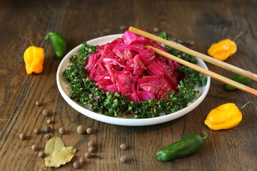 Korean cabbage salad with beets on a plate with pepper. Delicious Asian cusine