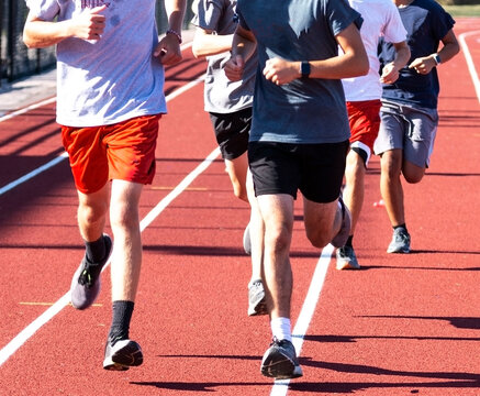 Close up of a group of boys running on a red track