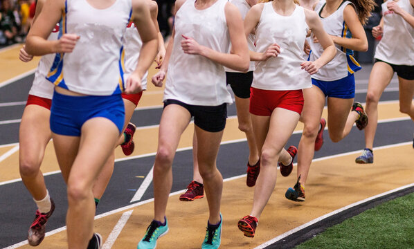 Group of girls running on an indoor track during a track meet
