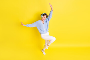 Above high angle view of lovely cheerful girl listening hit having fun dancing isolated over bright yellow color background