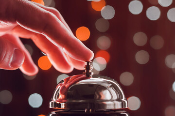 Hand pressing the hotel reception bell during Christmas holiday season