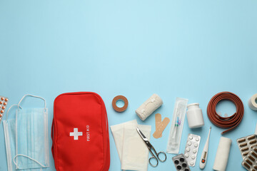 Flat lay composition with first aid kit on light blue background, space for text