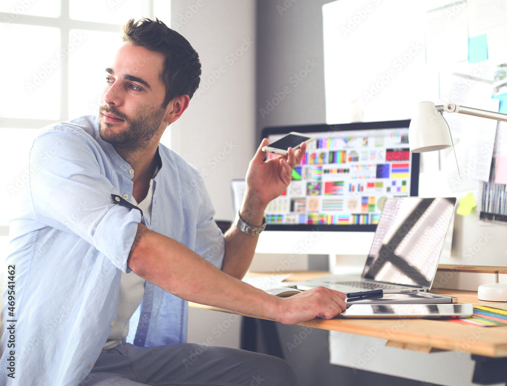 Poster portrait of young designer sitting at graphic studio in front of laptop and computer while working o