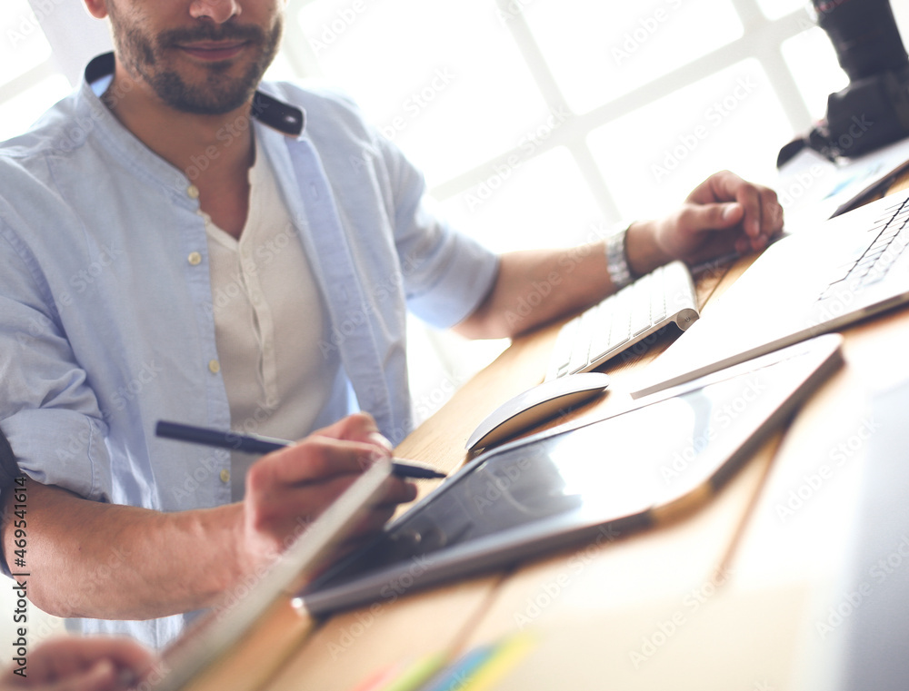 Poster portrait of young designer sitting at graphic studio in front of laptop and computer while working o