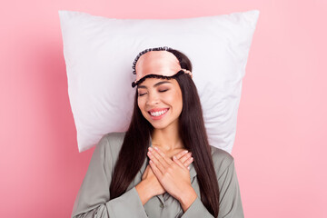 Photo of charming sweet lady sleepwear mask lying pillow arms chest smiling isolated pink color...