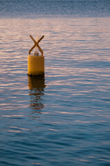 Yellow buoy floating in the sea with blue shades and evening light