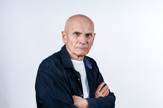 Evil elderly man crossed arms posing in studio with angry face expression.