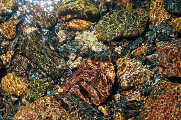 Rocks shimmering in the light of a river in the mountains 