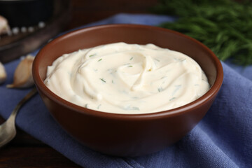 Tasty creamy dill sauce in bowl on blue kitchen towel, closeup