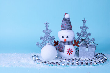 Snowman, gift, Christmas tree, Christmas ball on white snow on a blue background. Christmas New Year card. Place for an inscription.