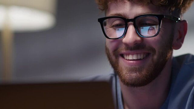 Smiling Hipster Man Looking to Laptop. Male Student Talking With Friend Using Laptop Computer Video Conference Calling Chat Sitting at Home.