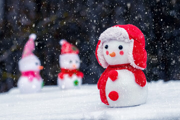 Snowmen in the snow on a dark background during a snowfall
